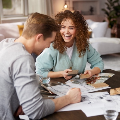 Ein Pärchen sitzt am Esstisch bei Weser Wohnwelt und plant voller Vorfreude die Einrichtung ihrer Traumwohnung mit stilvollen Interliving Möbeln.