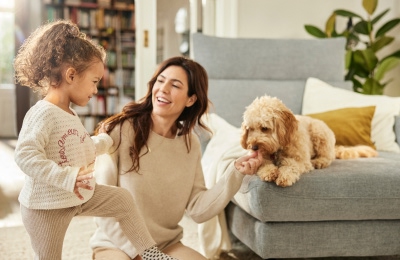 Lachende Mutter mit Hund und Kind in einem schönen Wohnzimmer – harmonische Wohnatmosphäre mit Wohlfühlcharakter.